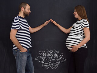 Image showing pregnant couple drawing their imaginations on chalk board