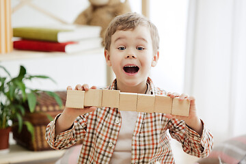 Image showing Little child sitting on the floor. Pretty boy palying with wooden cubes at home