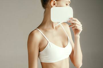 Image showing Young adult woman holding empty paper card for sign or symbol.