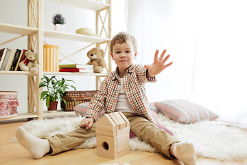 Image showing Little child sitting on the floor. Pretty boy palying with wooden cubes at home