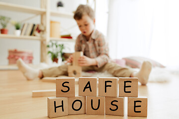 Image showing Wooden cubes with words SAFE HOUSE in hands of little boy