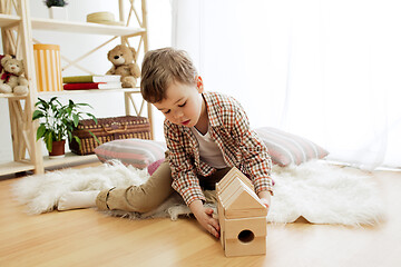 Image showing Little child sitting on the floor. Pretty boy palying with wooden cubes at home