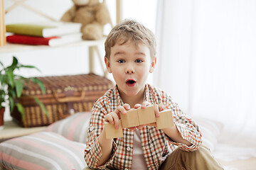 Image showing Little child sitting on the floor. Pretty boy palying with wooden cubes at home