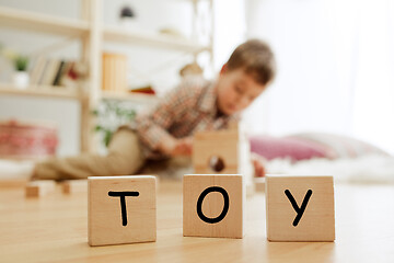 Image showing Wooden cubes with word TOY in hands of little boy