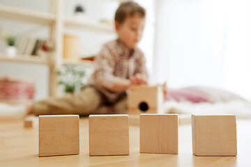 Image showing Little child sitting on the floor. Pretty boy palying with wooden cubes at home