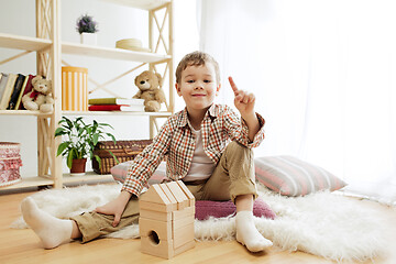 Image showing Little child sitting on the floor. Pretty boy palying with wooden cubes at home