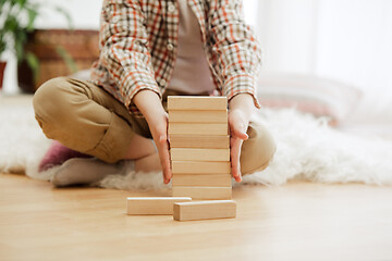 Image showing Little child sitting on the floor. Pretty boy palying with wooden cubes at home