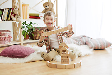 Image showing Little child sitting on the floor. Pretty boy palying with wooden cubes at home