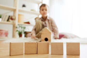 Image showing Little child sitting on the floor. Pretty boy palying with wooden cubes at home