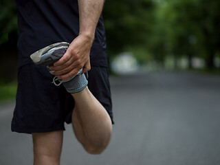 Image showing male runner warming up and stretching before morning training