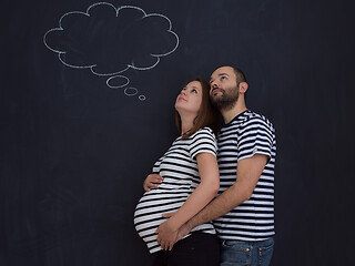 Image showing pregnant couple posing against black chalk drawing board