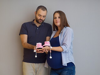 Image showing pregnant couple holding newborn baby shoes