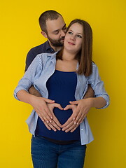 Image showing pregnant couple  isolated over yellow background