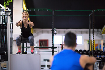 Image showing woman working out with personal trainer jumping on fit box