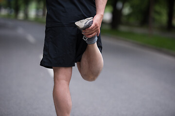 Image showing male runner warming up and stretching before morning training