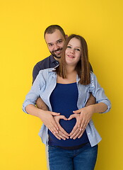 Image showing pregnant couple  isolated over yellow background