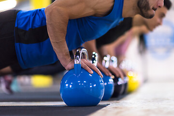 Image showing young athletes doing pushups with kettlebells