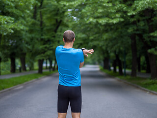 Image showing male runner warming up and stretching before morning training