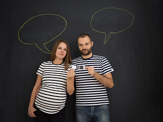 Image showing pregnant couple posing against black chalk drawing board