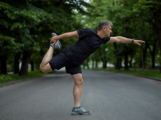 Image showing male runner warming up and stretching before morning training