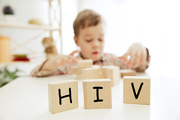 Image showing Wooden cubes with word HIV in hands of little boy at home.