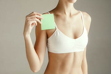 Image showing Young adult woman holding empty paper card for sign or symbol.