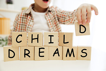 Image showing Wooden cubes with words CHILD DREAMS in hands of little boy