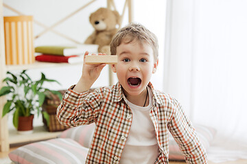 Image showing Little child sitting on the floor. Pretty boy palying with wooden cubes at home