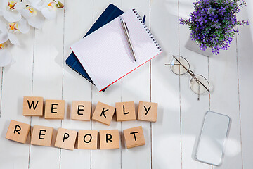 Image showing WEEKLY REPORT. Message at wooden cubes on a desk background.