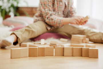 Image showing Little child sitting on the floor. Pretty boy palying with wooden cubes at home