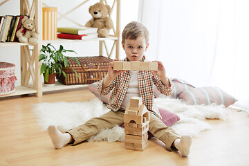 Image showing Little child sitting on the floor. Pretty boy palying with wooden cubes at home