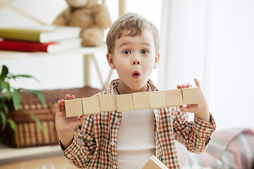 Image showing Little child sitting on the floor. Pretty boy palying with wooden cubes at home