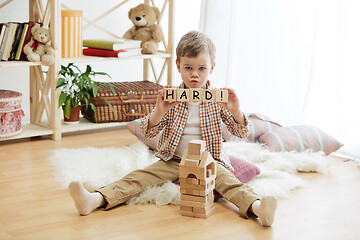 Image showing Wooden cubes with word HARD in hands of little boy