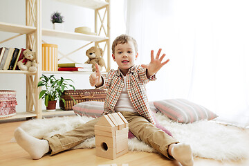 Image showing Little child sitting on the floor. Pretty boy palying with wooden cubes at home