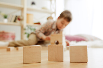 Image showing Little child sitting on the floor. Pretty boy palying with wooden cubes at home