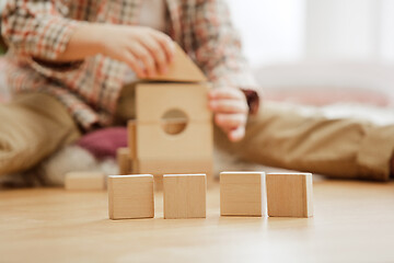 Image showing Little child sitting on the floor. Pretty boy palying with wooden cubes at home