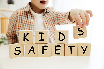 Image showing Wooden cubes with words KIDS SAFETY in hands of little boy