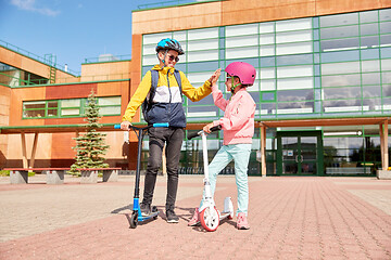 Image showing happy school children with backpacks and scooters