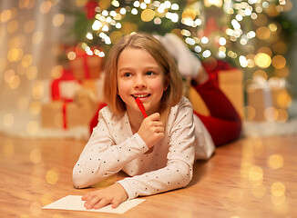 Image showing smiling girl writing christmas wish list at home