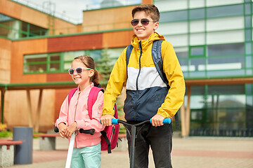 Image showing happy school children with backpacks and scooters