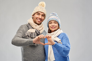 Image showing happy couple in winter clothes making hand heart