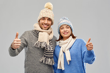 Image showing happy couple in winter clothes showing thumbs up