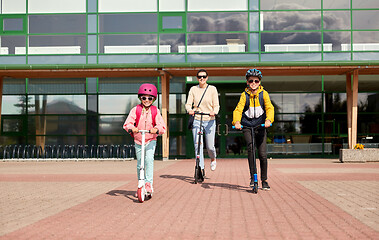 Image showing happy school children with mother riding scooters