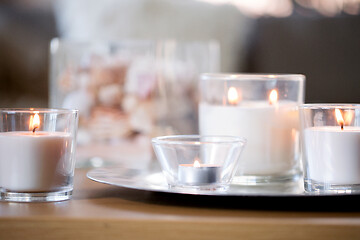 Image showing burning white fragrance candles on tray on table