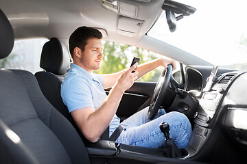 Image showing man driving car and using smartphone