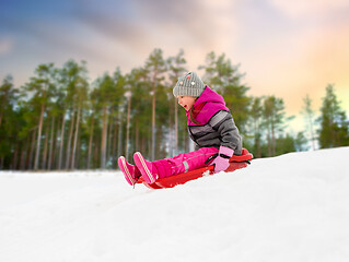 Image showing happy little girl sliding down on sled in winter