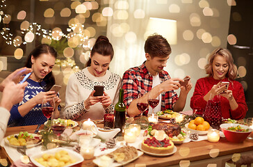 Image showing friends with smartphones having christmas dinner