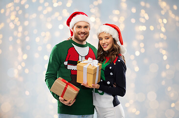 Image showing happy couple in sweaters with christmas gifts