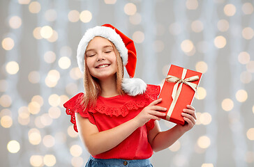 Image showing pleased girl in santa hat with christmas gift