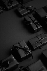 Image showing Arranged Gifts boxes wrapped in black paper with black ribbon on black background. Christmas concept